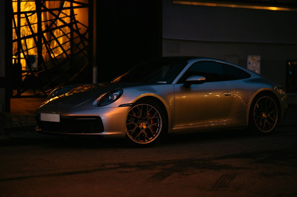 A silver sports car parked under warm amber light at night